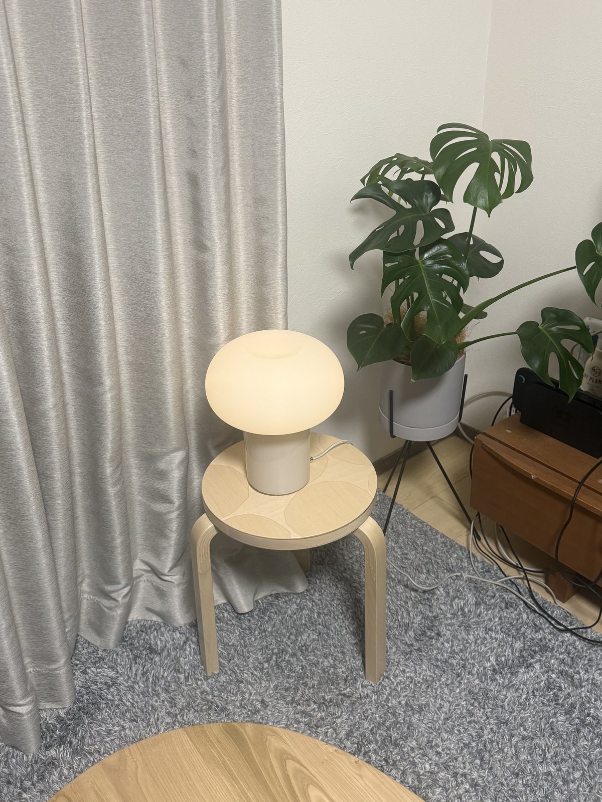我が家のリビングの片隅。アルテックのスツール60キヴェット（座面に石模様の象嵌）の上に、IKEAのきのこ型ランプ。隣にモンステラの鉢
